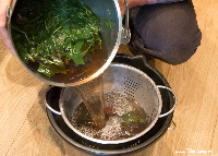 Straining woad leaves in a colander | woad.org.uk